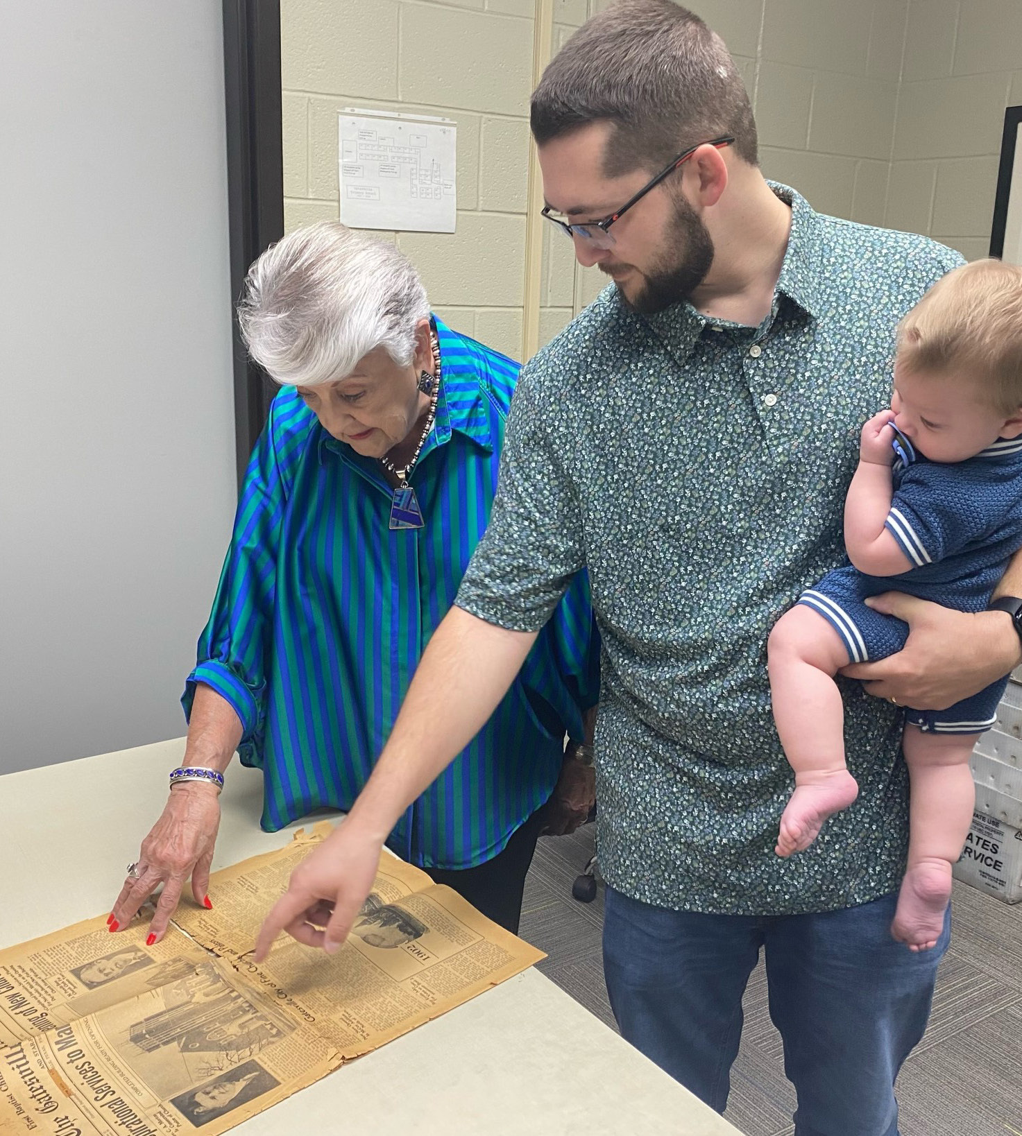 Cathy Taylor and Rev. Talon Keeney examine the 1936 edition of The Gatesville Messenger which announced the dedication of First Baptist Church’s new building. Kenney is pictured holding his son, Shepherd. The Gatesville Messenger | David Scott
