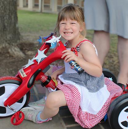 Tyler Hrometz, left, and Bentlee Lamb compare their bicycles, decorated in red, white and blue, before joining the Central Texas College Child Development Center Patriotic Parade celebrating America’s 250th birthday. RIGHT: Fiveyear- old Claudia Putzer cruises through thep arade on her Big Wheel. COURTESY PHOTO