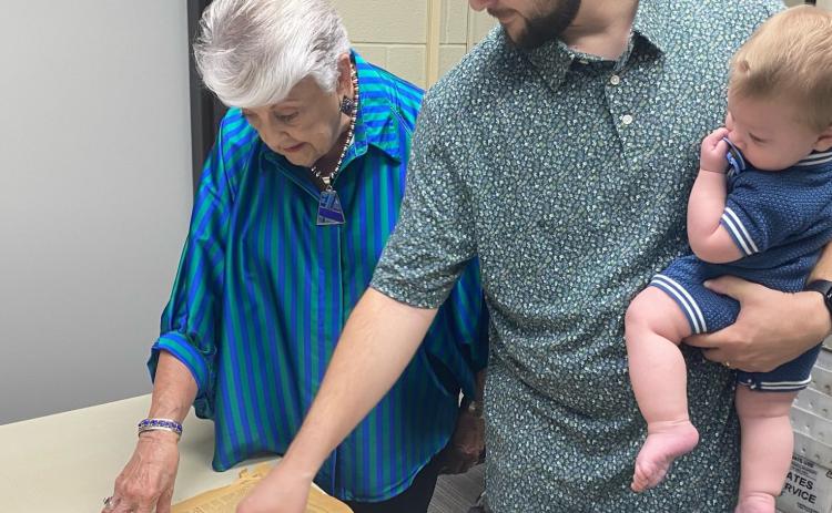 Cathy Taylor and Rev. Talon Keeney examine the 1936 edition of The Gatesville Messenger which announced the dedication of First Baptist Church’s new building. Kenney is pictured holding his son, Shepherd. The Gatesville Messenger | David Scott
